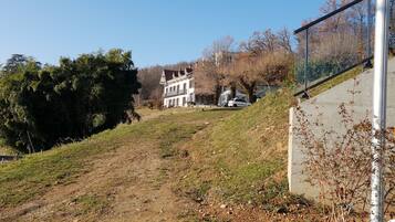 A hillside with a white building, a clear sky, and a fence.