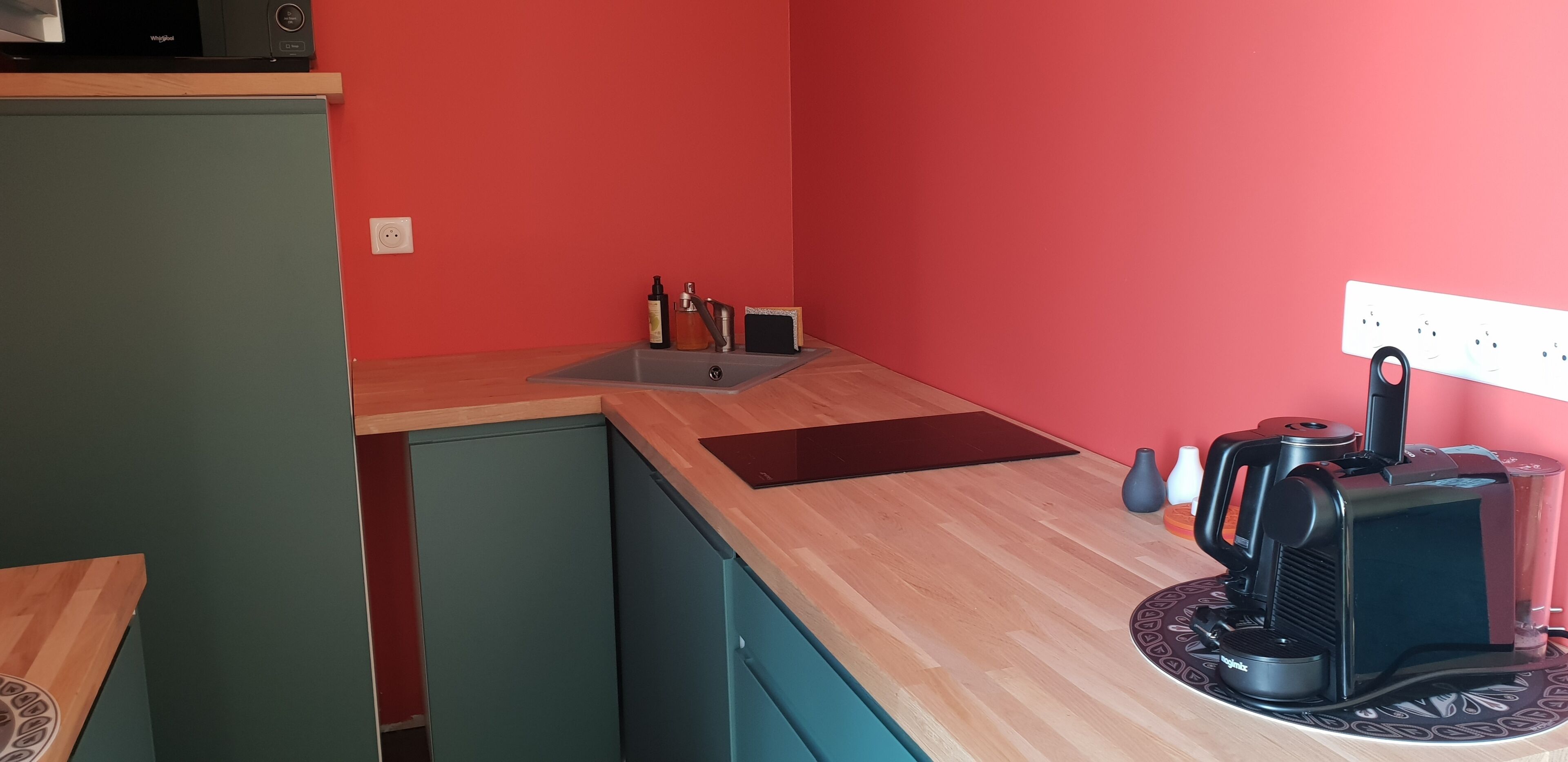 A compact kitchen with a microwave, sink, and coffee machine.