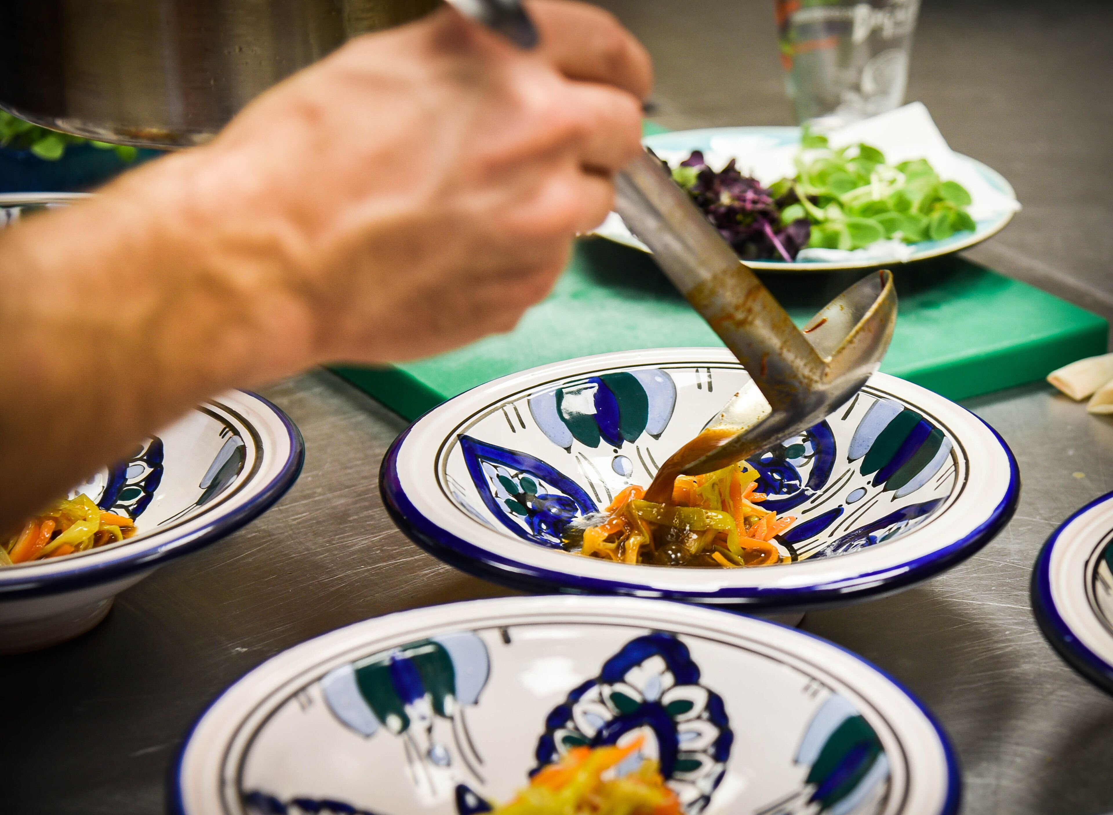 A person serving food from a bowl onto a plate.