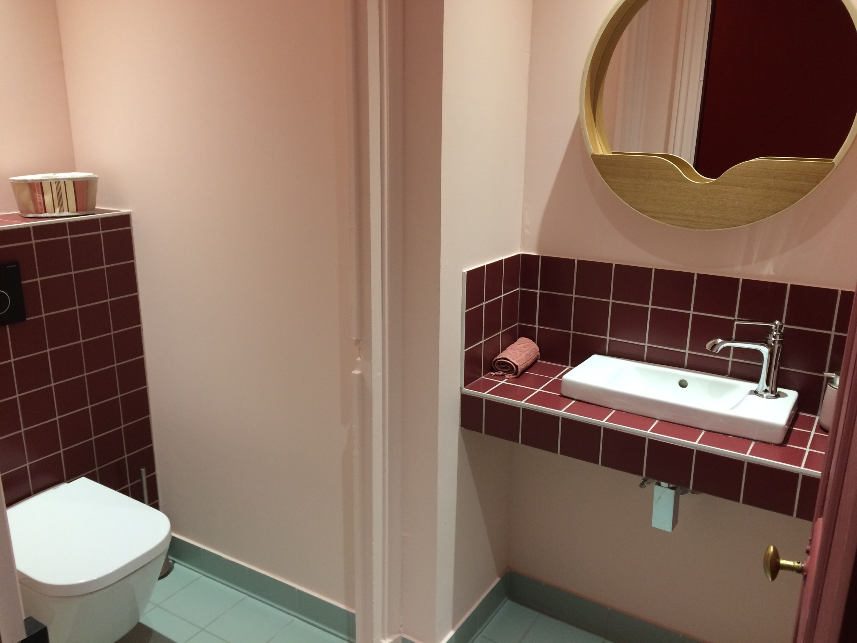 Un baño con un inodoro blanco, un lavabo con un espejo encima y una toalla sobre el lavabo.