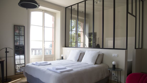 Un dormitorio con una cama grande, una ventana, un espejo y una silla roja.