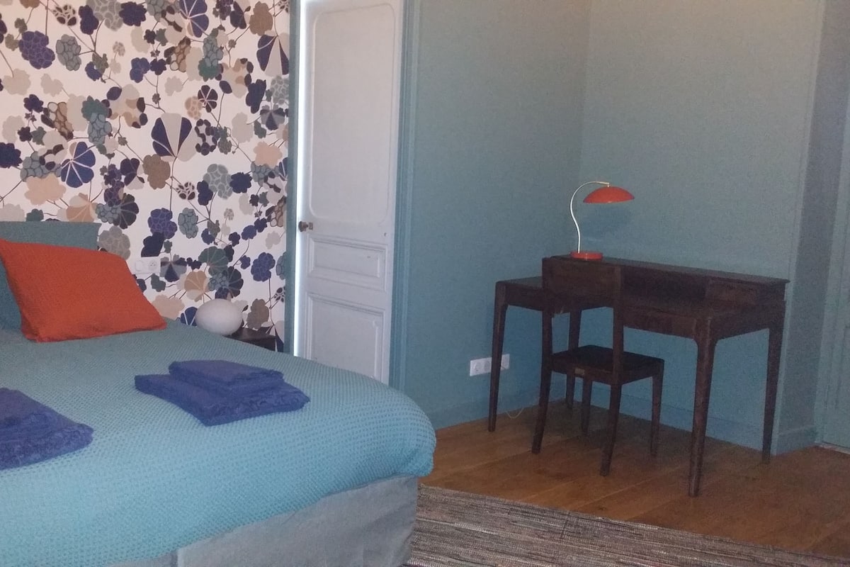 A bedroom with a bed, a desk, and a chair.