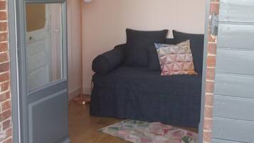 Une pièce chaleureuse avec un canapé bleu foncé, un tapis à motifs et une lampe sur pied.