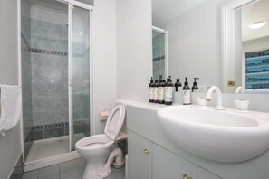 A bathroom with a toilet, a shower, and a sink with toiletries. - 3 Bedrooms 2 Car Parks Carlton Garden Opposite (Melbourne)