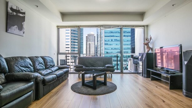 A modern living room with a leather sofa, a coffee table, and a TV on a stand. - 3 Bedrooms 2 Car Parks Carlton Garden Opposite (Melbourne)