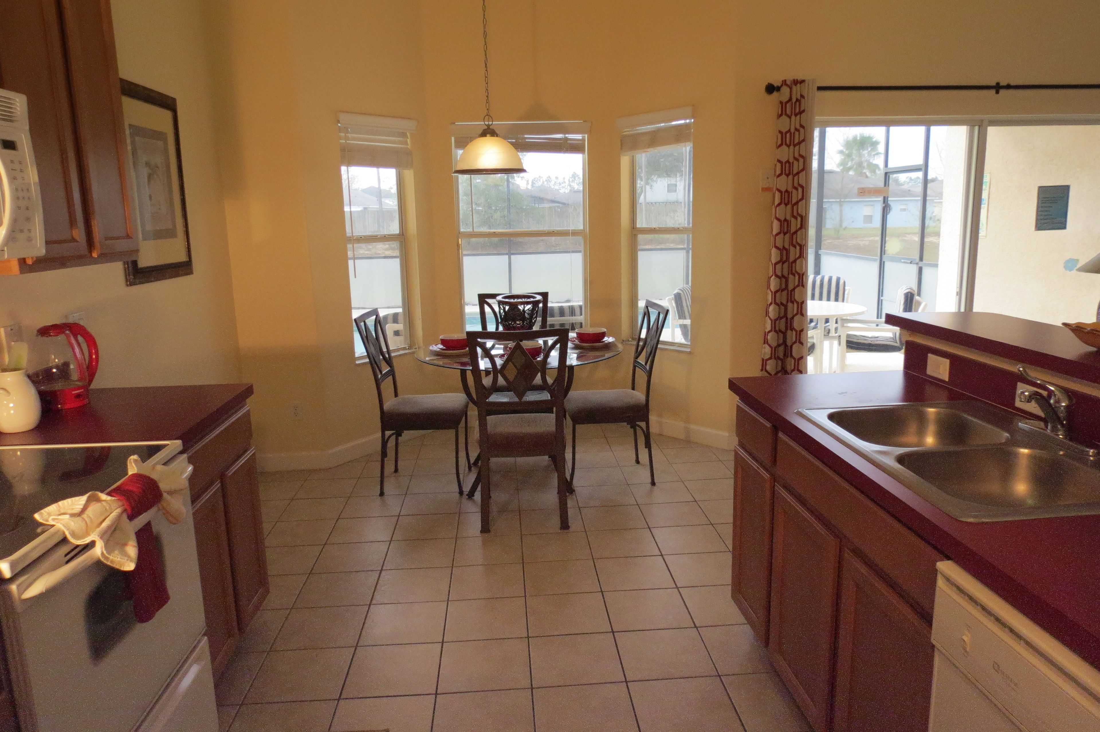A kitchen with a dining table, chairs, a microwave, a coffee maker, and a sink.