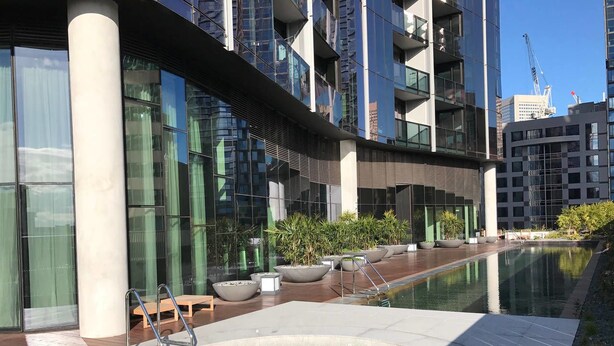 A modern building with a swimming pool, outdoor seating, and large windows. - Central But Quiet Apartment (Melbourne)