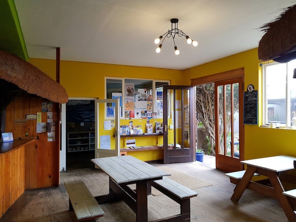 A room with wooden benches, a thatched roof, and a wall with various informational posters.