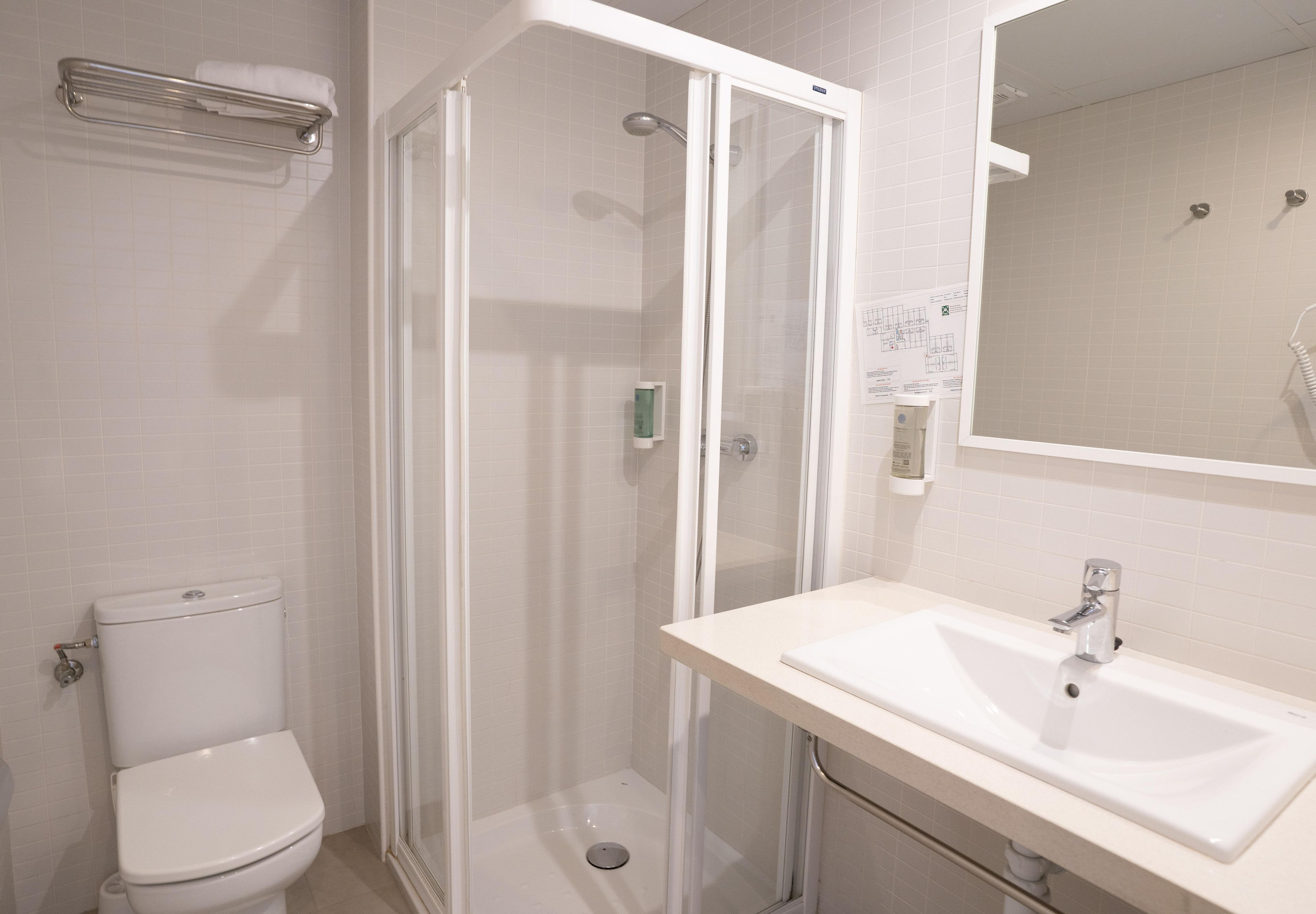 A bathroom with a toilet, a shower enclosure, and a sink.