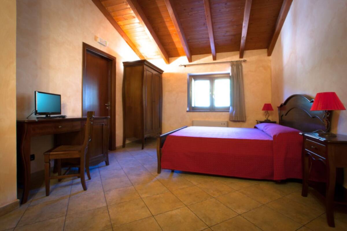 Een slaapkamer met een bed, een bureau, een stoel, een raam en een deur.