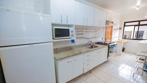 Una cocina moderna con armarios blancos, un microondas, una estufa y un lavabo.