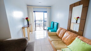 Una sala de estar moderna con un sofá, un sillón y una mesita con un jarrón de flores.