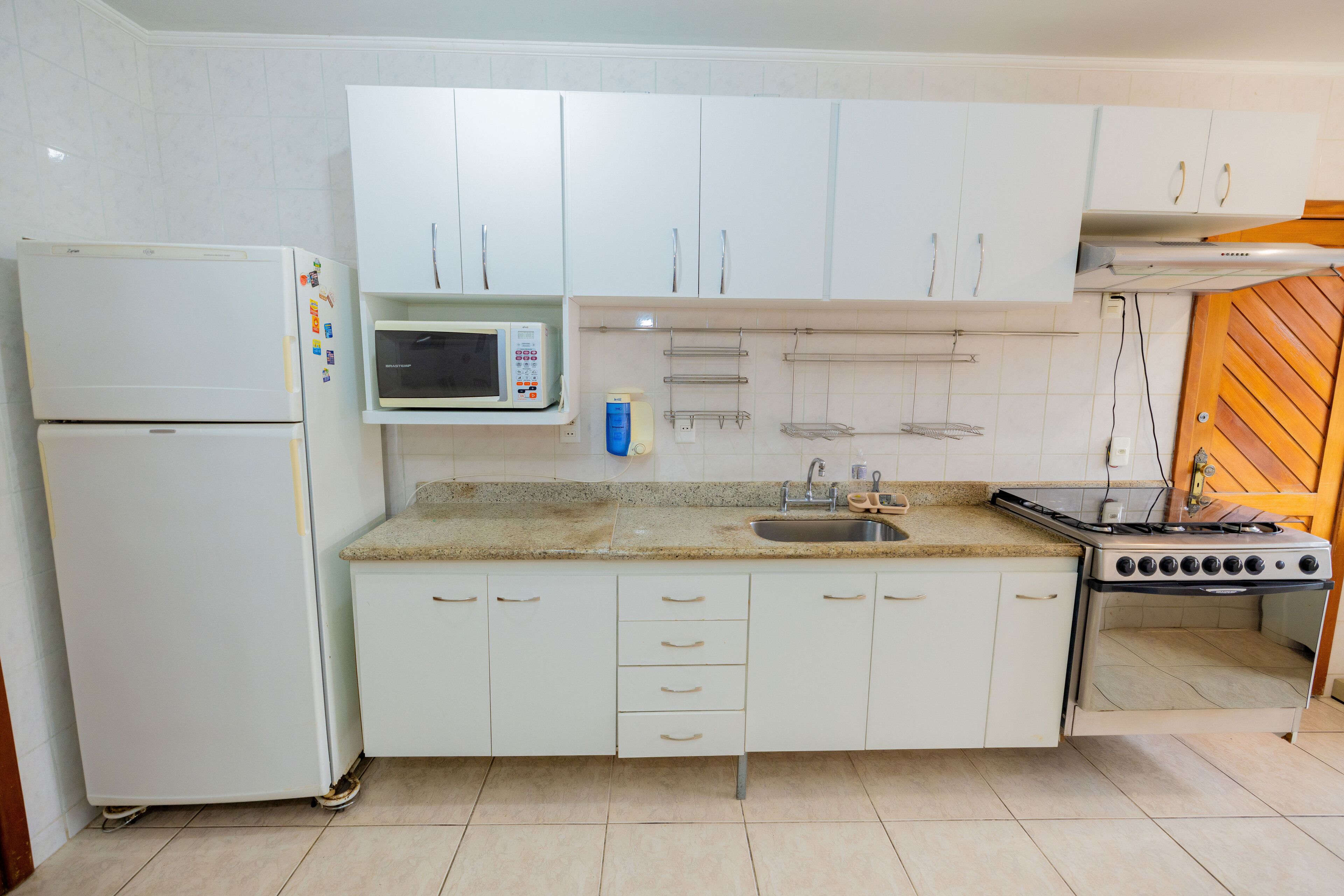 A kitchen with white cabinets, a microwave, a stove, and a refrigerator.