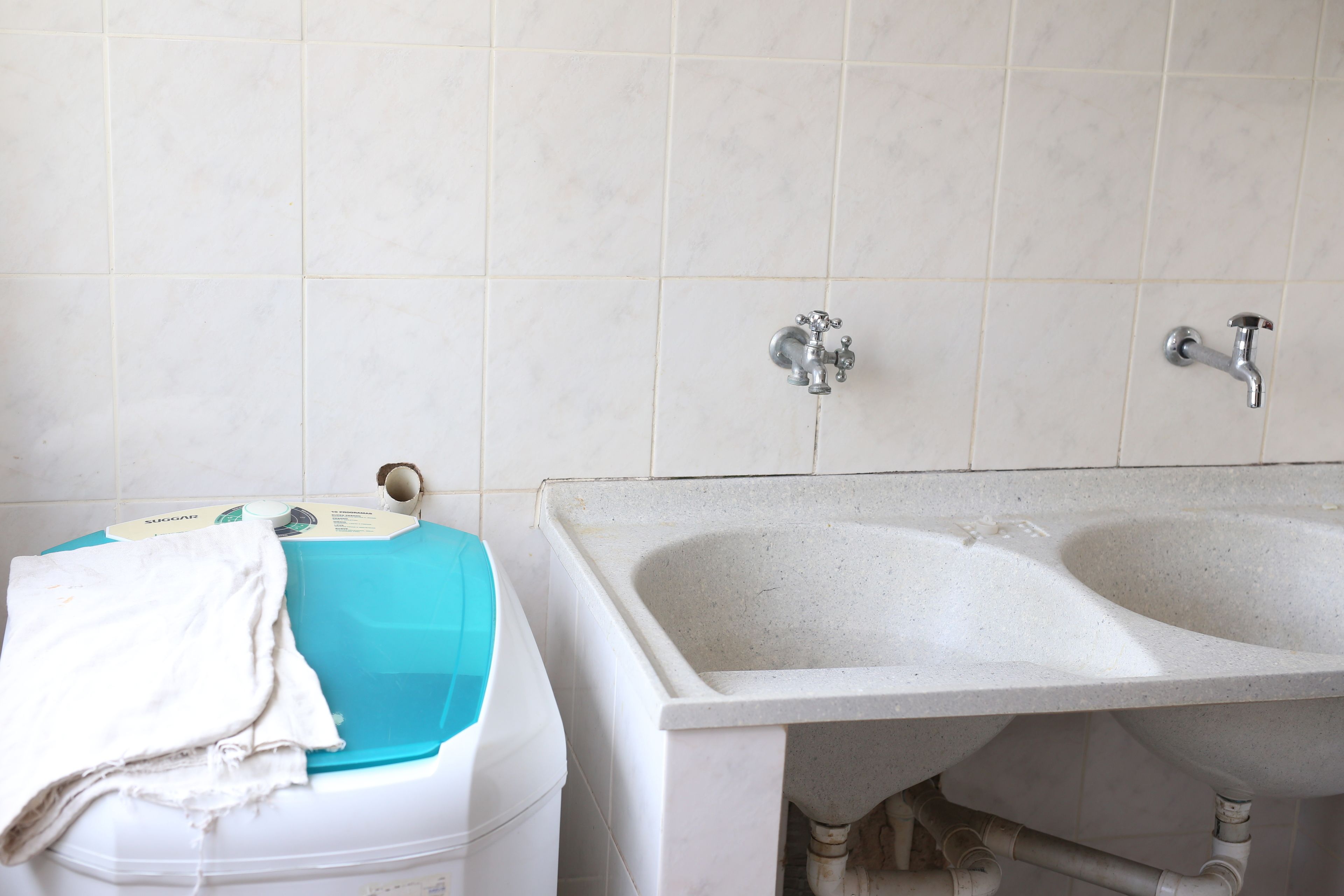 A bathroom with a white sink, two faucets, and a blue basin.