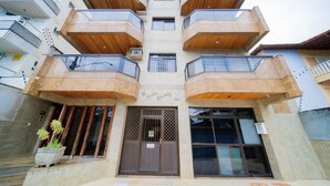 Un immeuble à plusieurs étages doté d’une entrée centrale, de balcons et d’une plante en pot à l’extérieur.