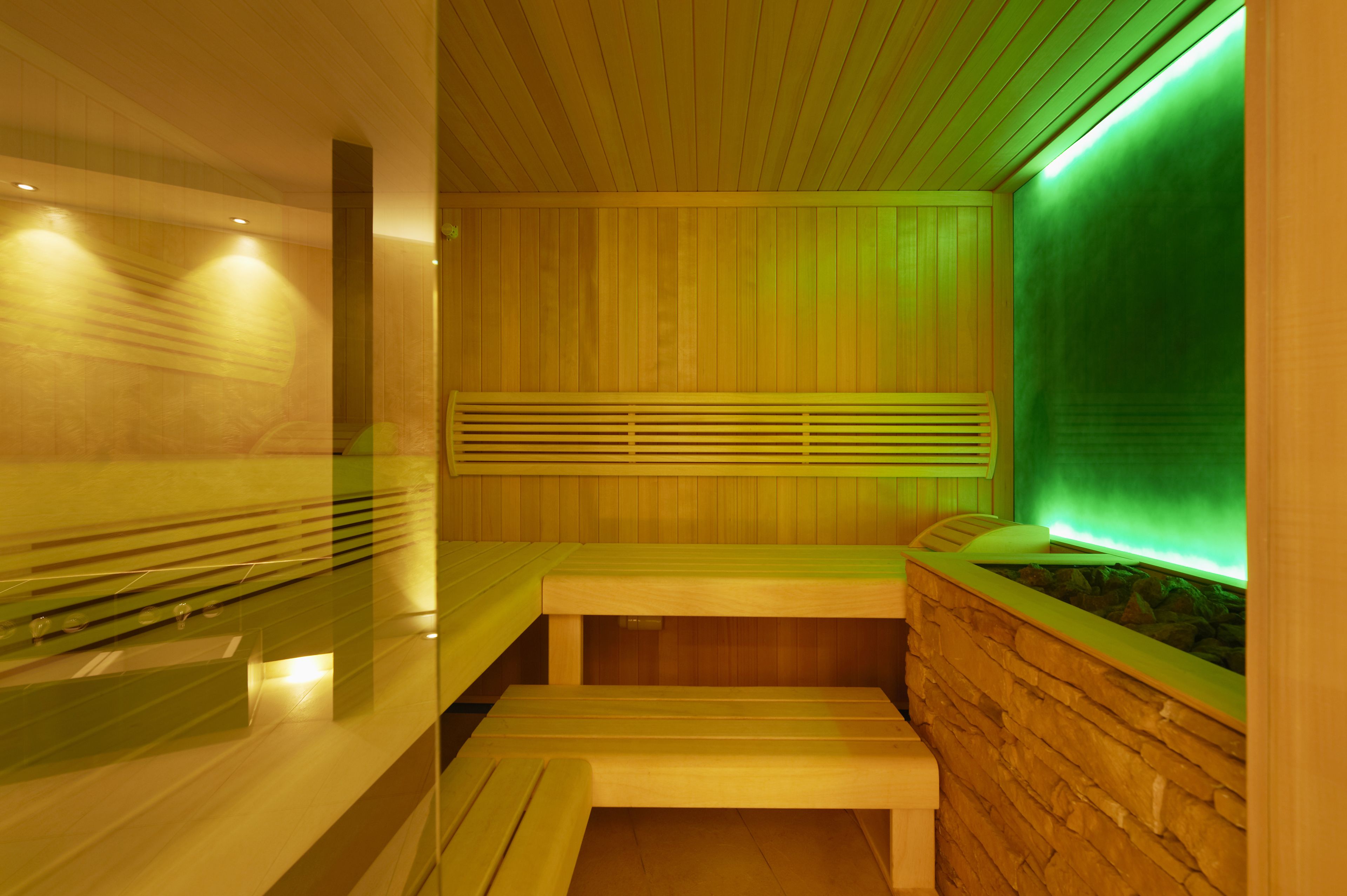 A sauna with wooden benches and a stone wall.