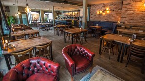 Un restaurant avec des tables et des chaises en bois, un coin bar et un mur en briques.