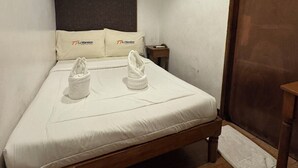 A single-bed room with a wooden headboard, white bedding, and two towels on the bed. - Sj Mansion Hotel (San Jose)