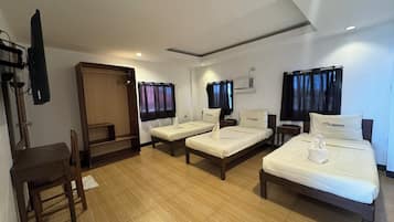 Habitación de hotel con dos camas individuales, un escritorio de madera, una silla, un televisor y un armario.