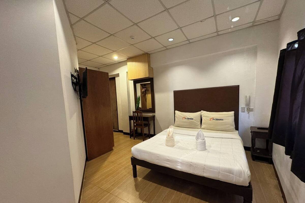 A hotel room with a bed, a desk, and a chair.