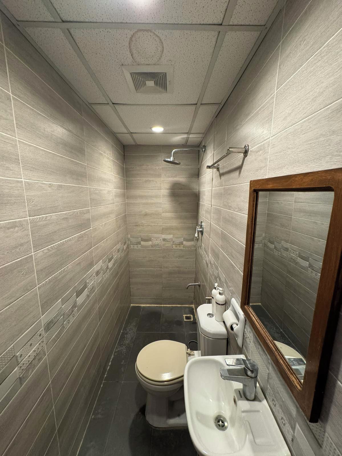 A small, tiled bathroom with a toilet, sink, and shower.