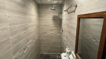 A small, tiled bathroom with a toilet, sink, and shower.