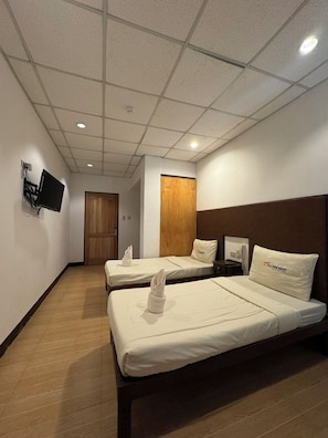 A hotel room with two beds, a TV mounted on the wall, and a wooden door. - Sj Mansion Hotel (San Jose)