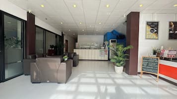 Una zona de recepción moderna con un mostrador, un espacio de estar y una planta grande en maceta.