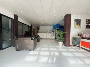A modern reception area with a reception desk, seating area, and a large potted plant. - Sj Mansion Hotel (San Jose)
