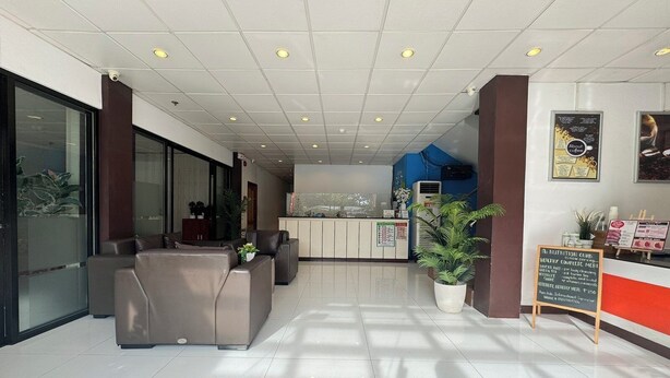A modern reception area with a reception desk, seating area, and a large potted plant. - Sj Mansion Hotel (San Jose)