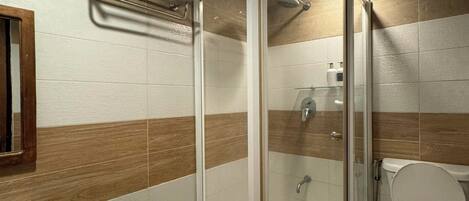 A modern bathroom with a glass-enclosed shower, a toilet, and a sink.