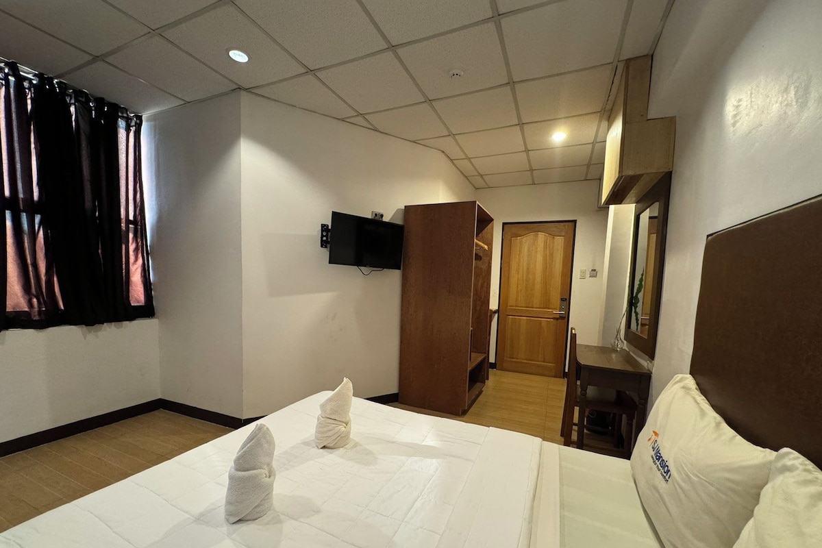 Une chambre d’hôtel équipée d’un lit, d’un bureau, d’une télévision et d’une armoire.