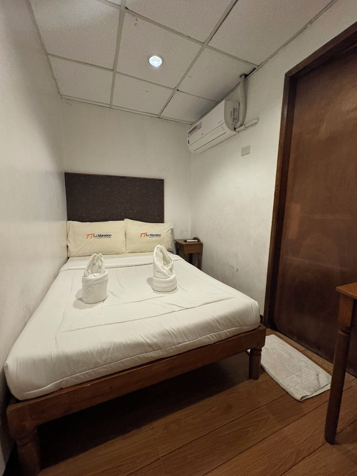 Ein Zimmer mit einem Einzelbett, einem hölzernen Kopfteil, weißer Bettwäsche und zwei Handtüchern auf dem Bett.