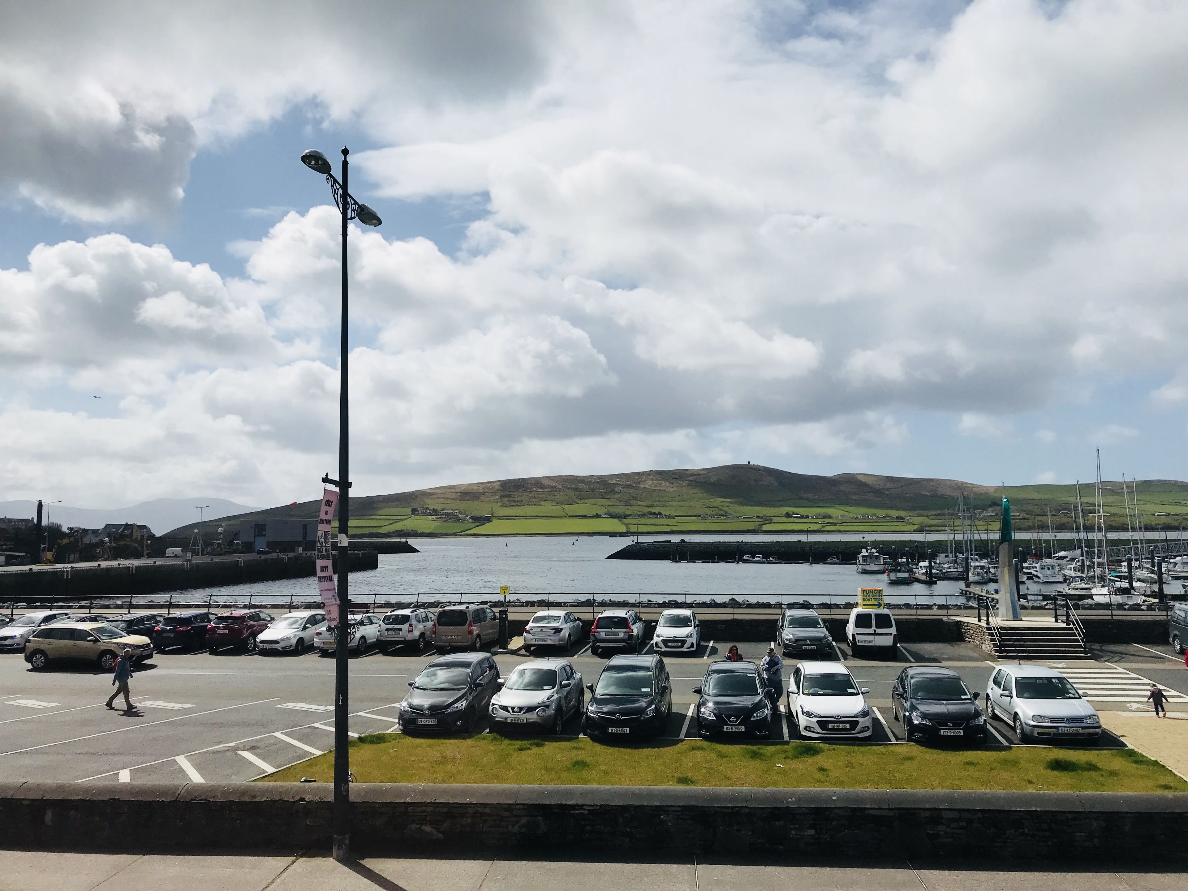 A parking lot with cars and a marina in the background.