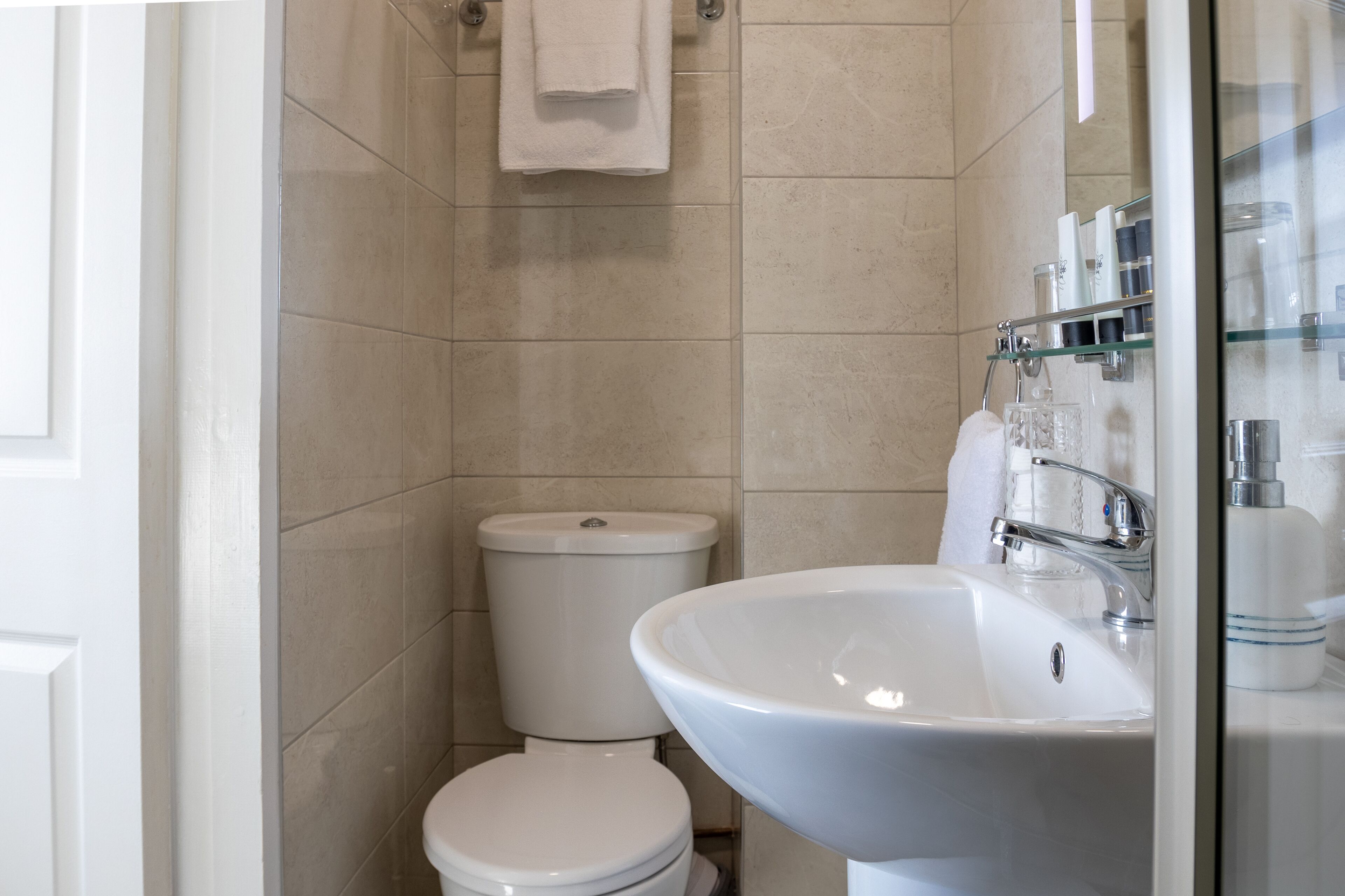A modern bathroom with a toilet, sink, and glass shower enclosure.
