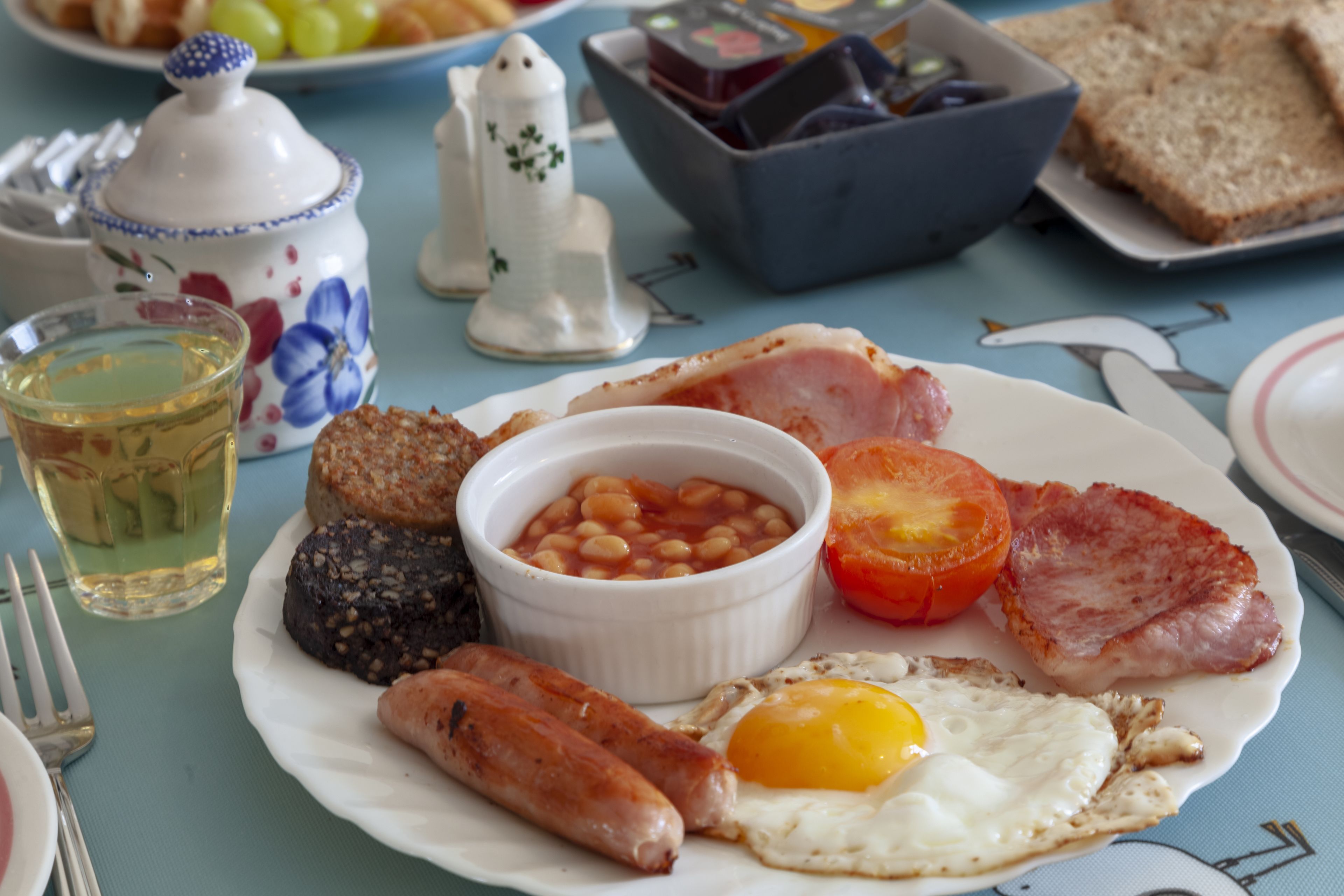 Un plato de desayuno con huevos, salchichas, frijoles, tocino y tomate.