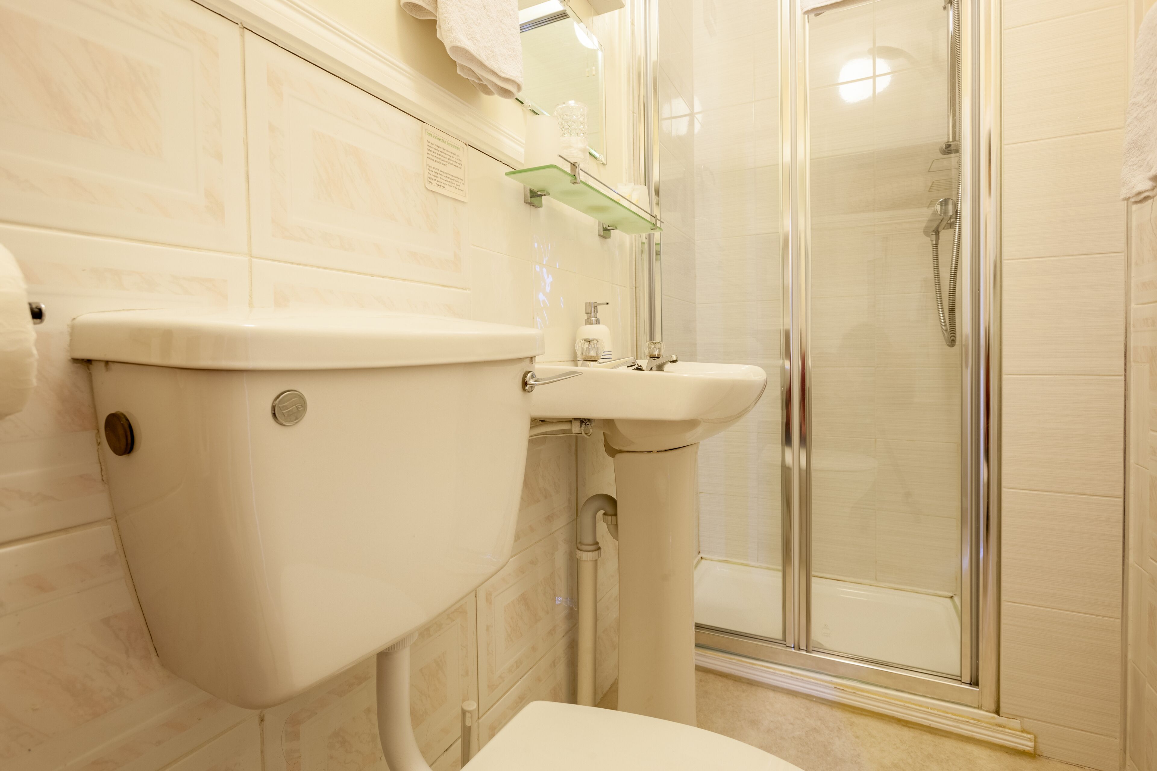 A bathroom with a toilet, sink, and glass-enclosed shower.