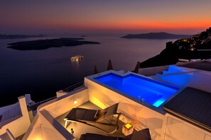 Ein Rooftop-Infinity-Pool mit Blick auf das Meer und ferne Inseln im Sonnenuntergang.