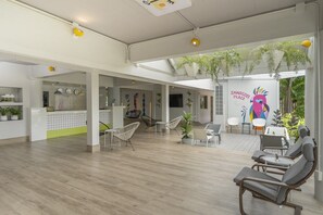 A spacious indoor area with a wooden floor, seating arrangements, and a wall with a colorful mural. - Sawasdee Place Hotel (Pattaya)