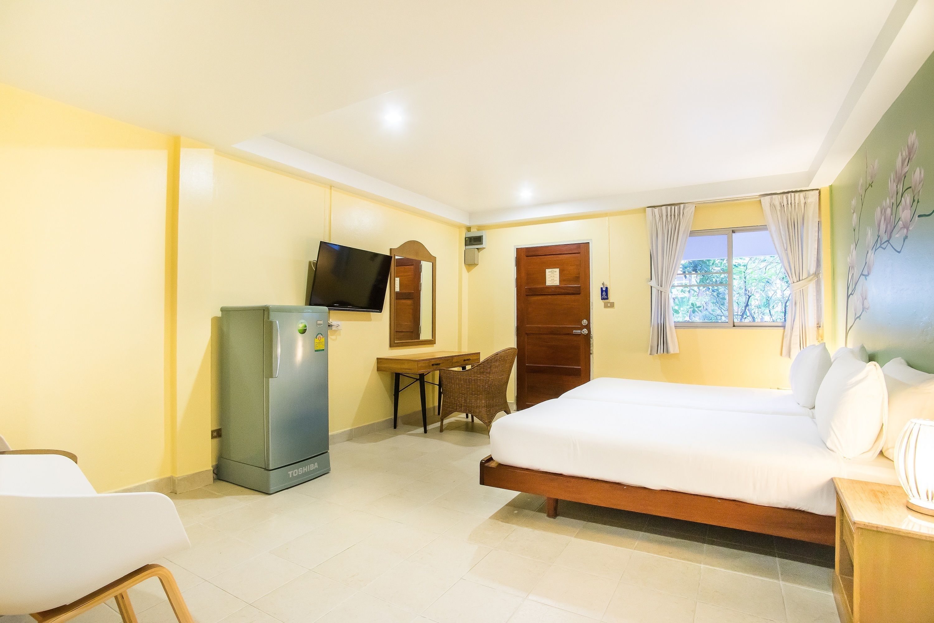 Una habitación de hotel con una cama, un escritorio, un televisor y un refrigerador.