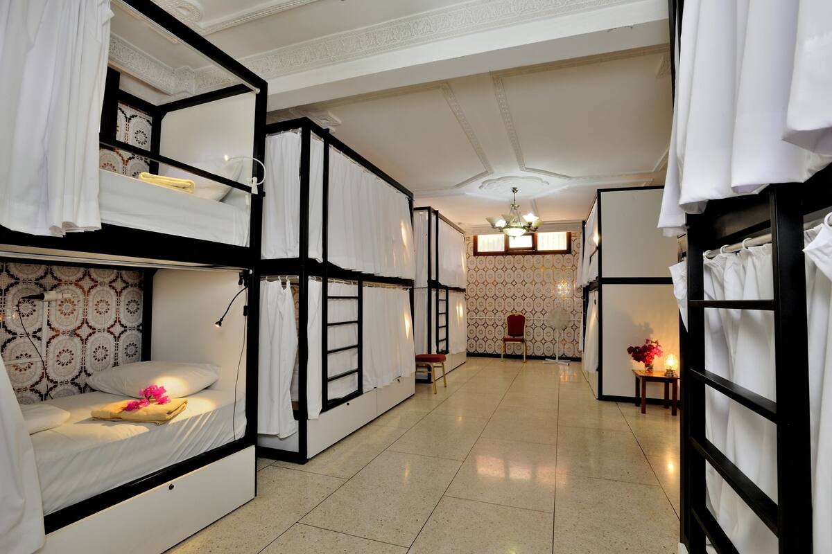Une chambre d’hôtel avec des lits superposés, une petite table avec un vase et une chaise.