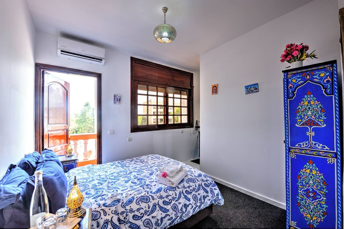 Une chambre à coucher avec un lit, une fenêtre, un climatiseur et une porte décorative.