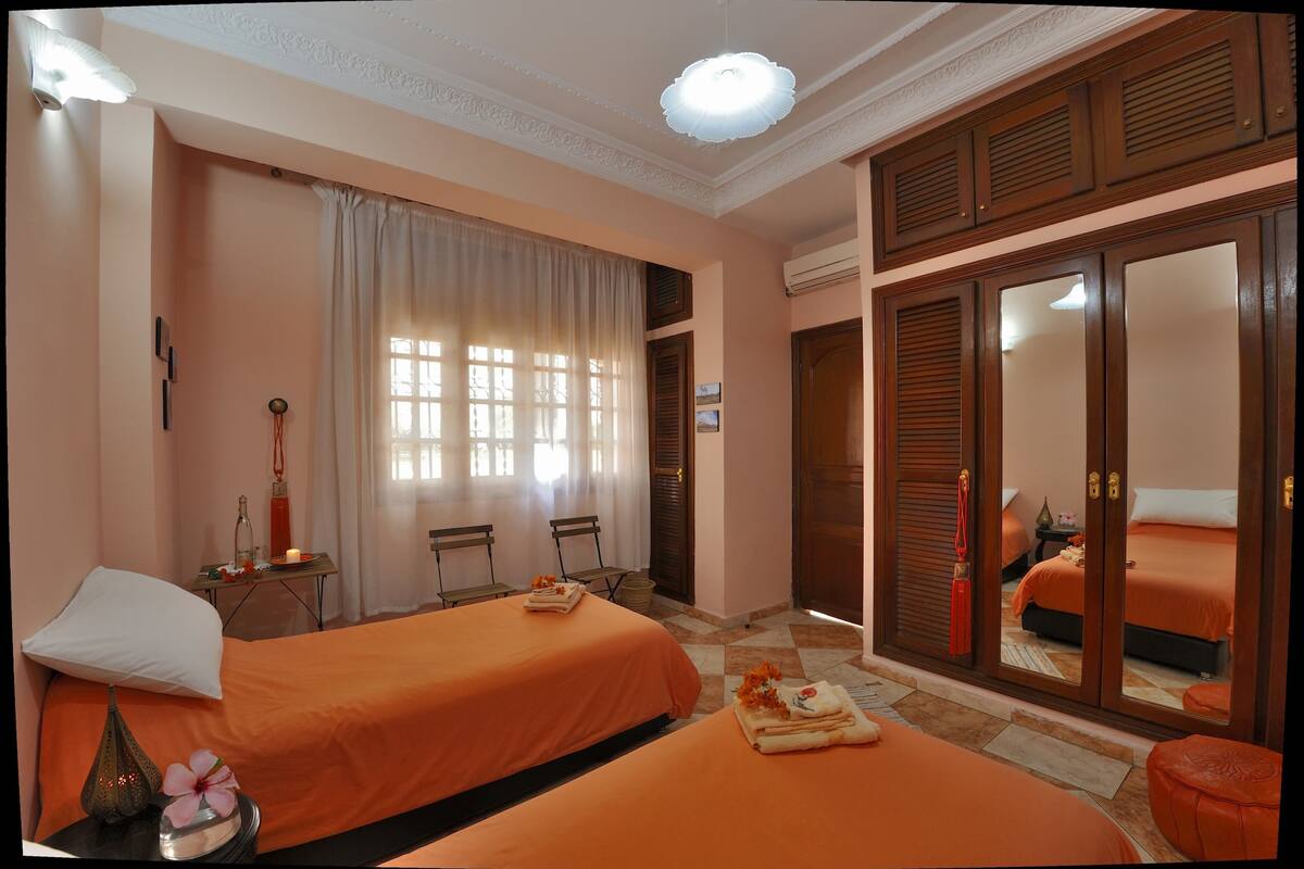 Une chambre d’hôtel avec deux lits, un coin salon avec une table et des chaises, un miroir et une armoire.