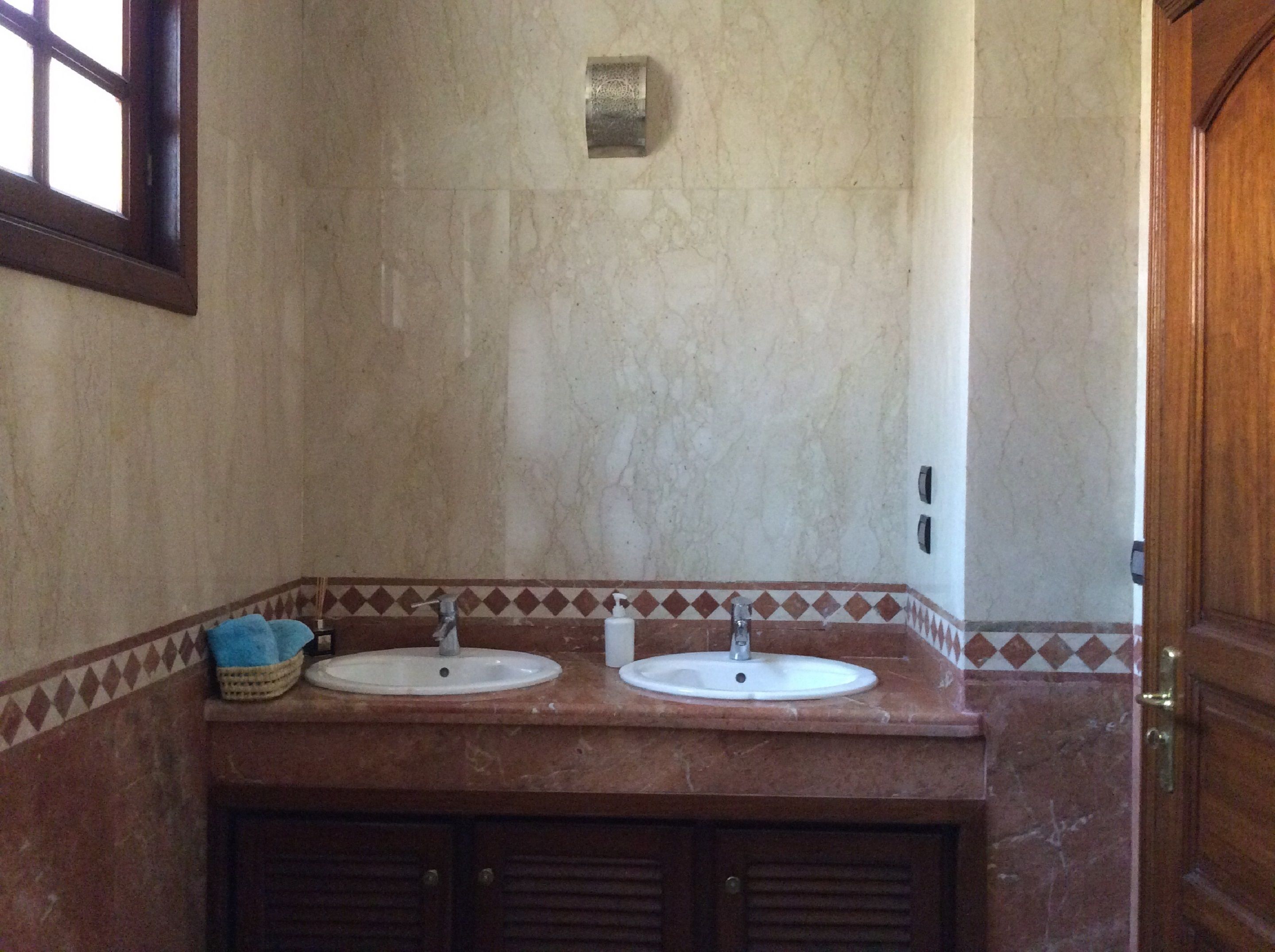 A bathroom with two sinks, a window, and a door.