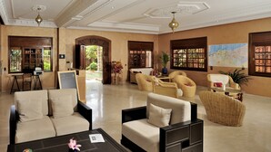 Eine geräumige Lobby mit einem beigefarbenen Sofa, einem Couchtisch, Korbstühlen und einer Karte an der Wand.