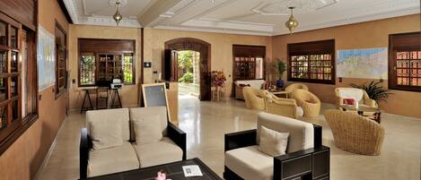 A spacious lobby with a beige sofa, a coffee table, wicker chairs, and a map on the wall.