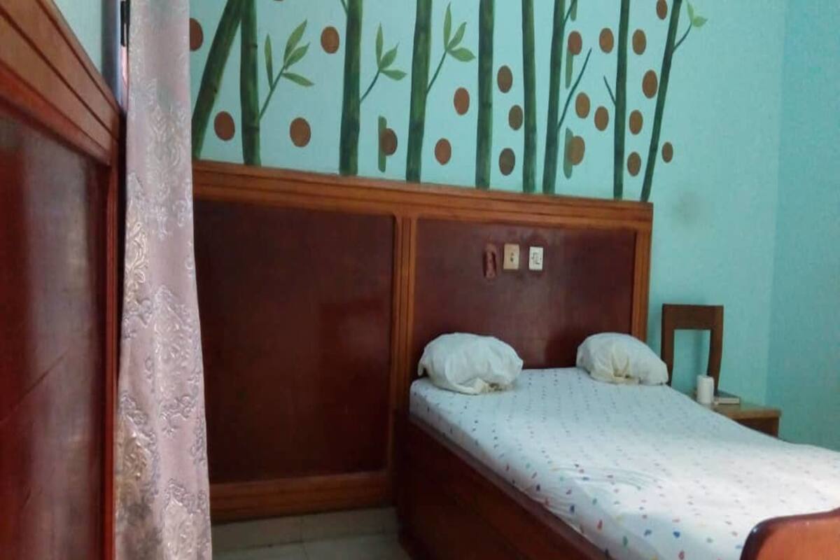 A bedroom with a wooden bed, a headboard with a clock, and a wall with a bamboo pattern.