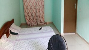 Een kamer met een bed, gordijn, airconditioning en een deur.