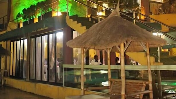 Een hotel met een grote, verlichte gevel, een terras en een trap naar de hogere verdiepingen.