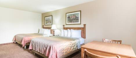 A hotel room with two beds, a wooden table, and a chair.